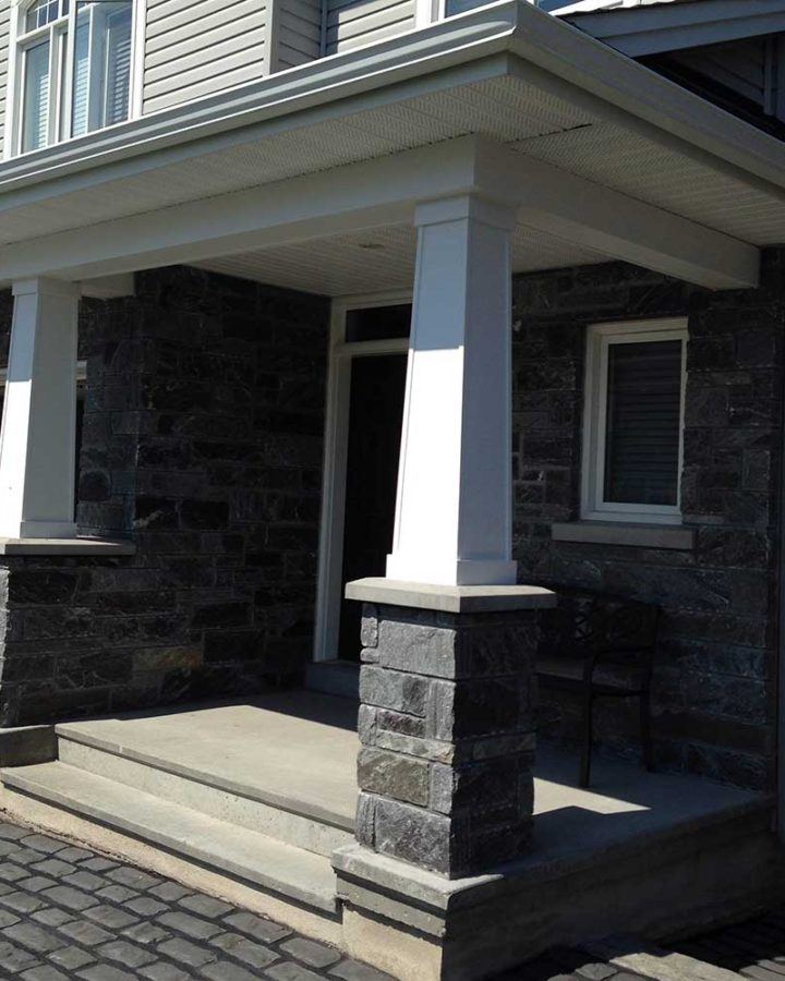 a stone house with a porch and columns