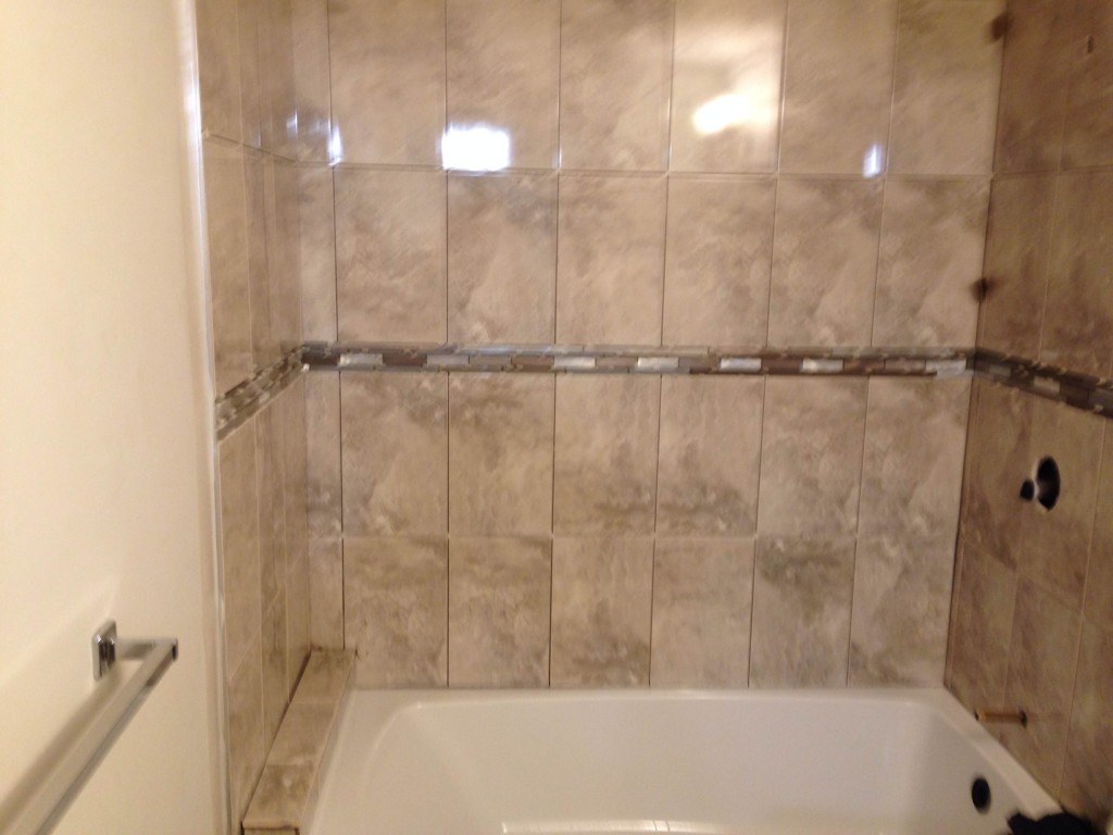 white ceramic bathtub near brown wall tiles