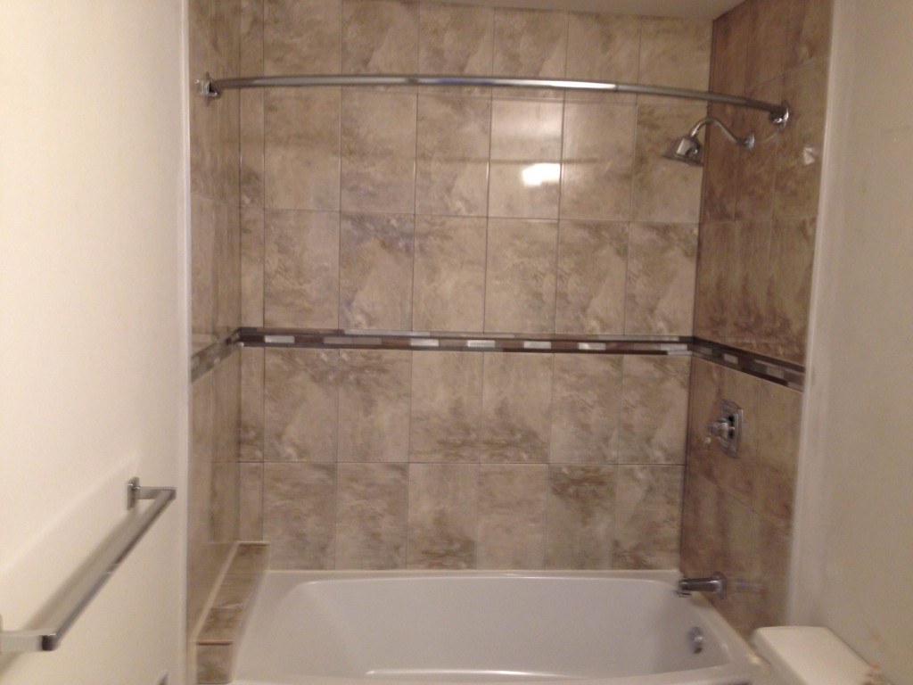 white ceramic bathtub near brown ceramic wall tiles